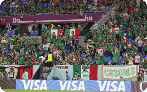 Mexican football fans in the stadium wearing national team jerseys.