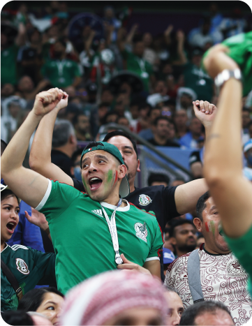 Excited football fans cheering in a stadium during a match.